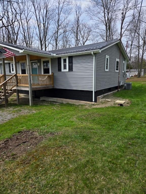 rear view of house featuring a lawn, central air condition unit, and metal roof