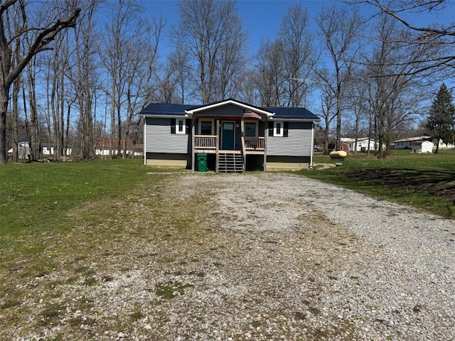 view of front facade with gravel driveway, metal roof, and a front lawn