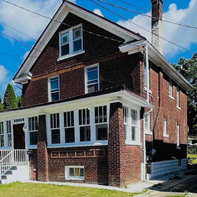 view of side of home featuring a chimney and brick siding