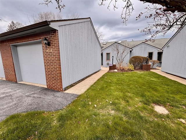 view of home's exterior featuring brick siding, a yard, and a garage