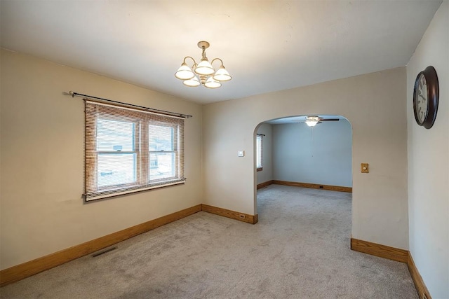 carpeted spare room with ceiling fan with notable chandelier