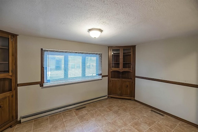 unfurnished room with baseboard heating and a textured ceiling