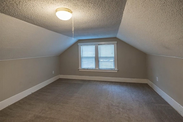 bonus room with vaulted ceiling, a textured ceiling, and dark carpet