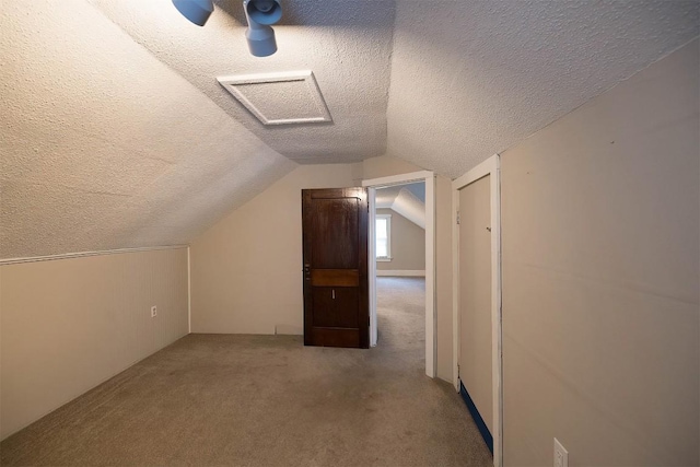 additional living space featuring light colored carpet, vaulted ceiling, and a textured ceiling