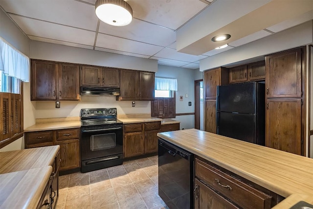 kitchen featuring a drop ceiling, dark brown cabinets, black appliances, and butcher block counters