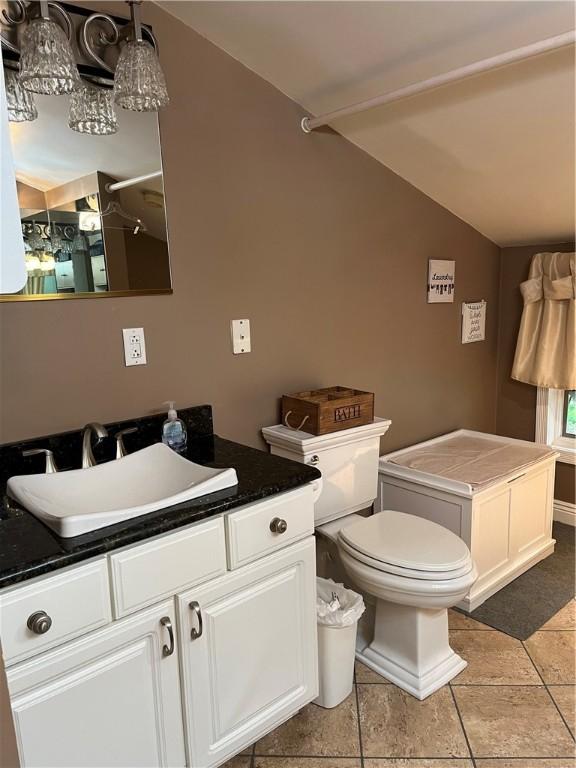 bathroom featuring tile patterned floors, vanity, toilet, and vaulted ceiling