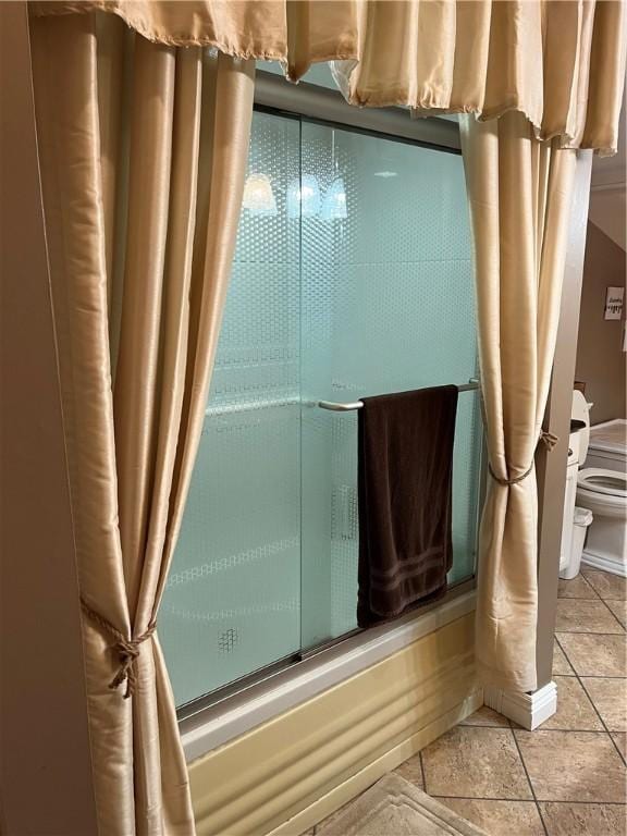 bathroom featuring toilet and bath / shower combo with glass door