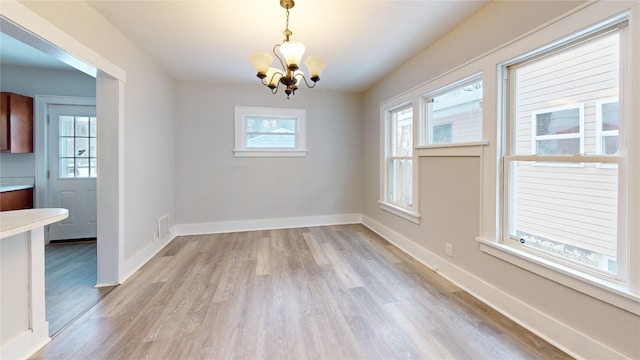 unfurnished dining area with light hardwood / wood-style flooring and a notable chandelier