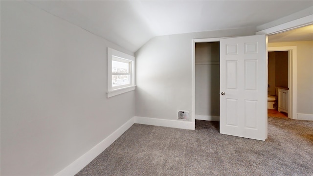 unfurnished bedroom with carpet flooring, a closet, and lofted ceiling