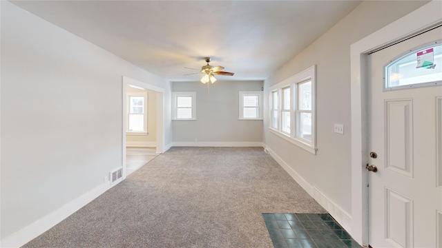 entrance foyer with ceiling fan and dark carpet