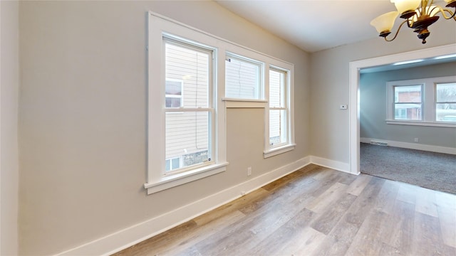 spare room with a chandelier and light hardwood / wood-style floors