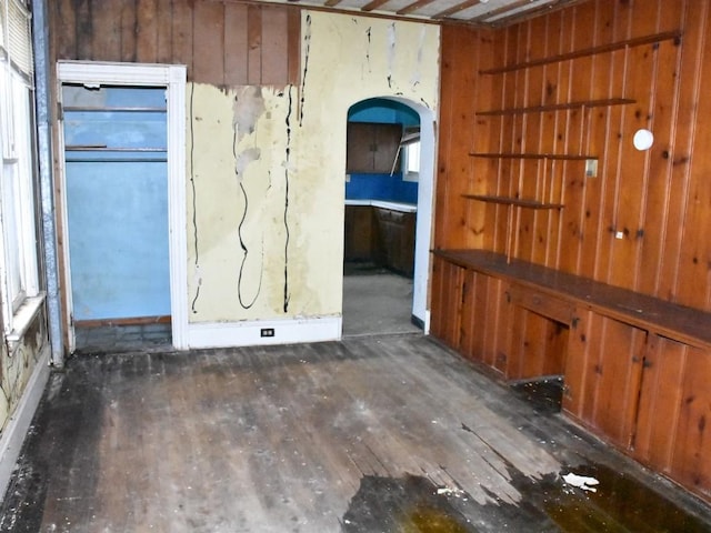 empty room with arched walkways and wood finished floors