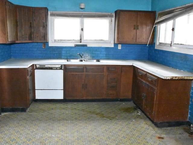 kitchen featuring white dishwasher, light countertops, a sink, and tasteful backsplash