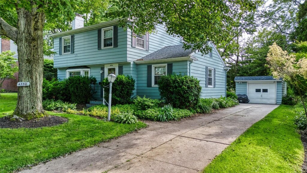 4330 Briggs Ave, Erie, PA 16504 - colonial-style house featuring an outdoor structure, a chimney, driveway, a detached garage, and a front lawn