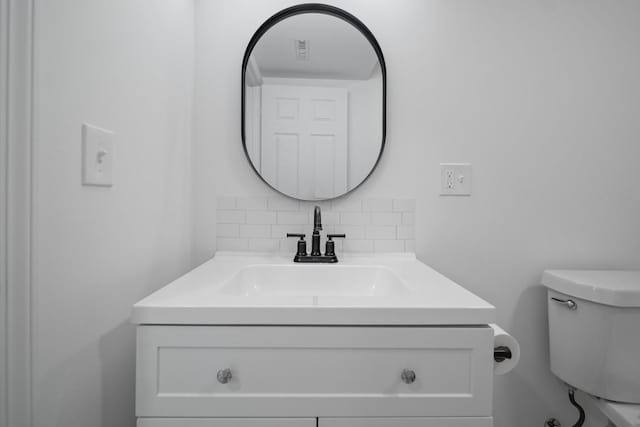 bathroom featuring tasteful backsplash, vanity, and toilet