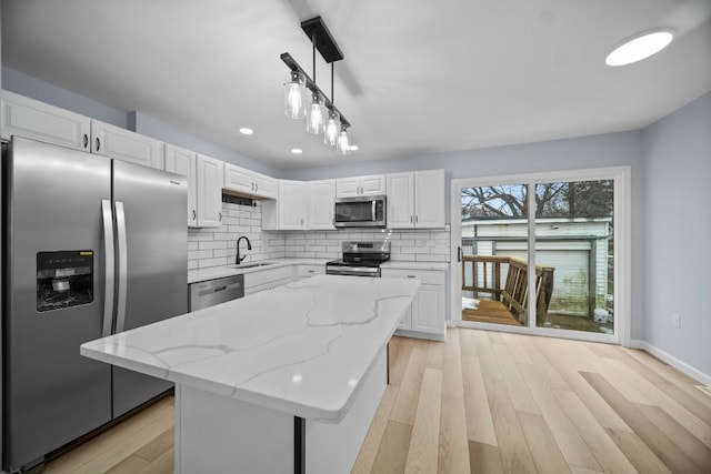 kitchen featuring pendant lighting, sink, appliances with stainless steel finishes, a center island, and white cabinets