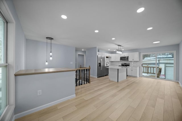 kitchen featuring appliances with stainless steel finishes, hanging light fixtures, a center island, tasteful backsplash, and white cabinets