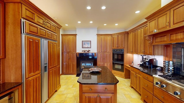 kitchen featuring stainless steel gas stovetop, a center island, crown molding, paneled built in refrigerator, and double oven