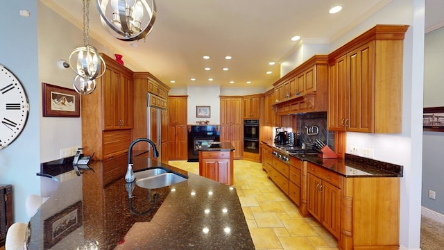 kitchen with dark stone counters, sink, decorative light fixtures, an inviting chandelier, and a center island