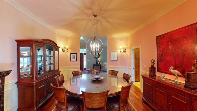 dining area with hardwood / wood-style floors, ornamental molding, and a notable chandelier