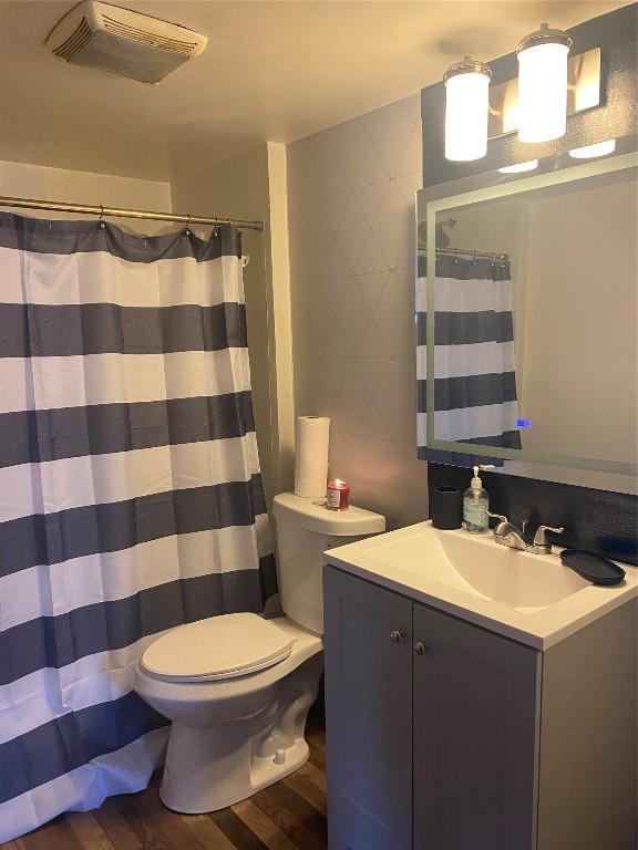 bathroom featuring toilet, hardwood / wood-style flooring, curtained shower, and vanity