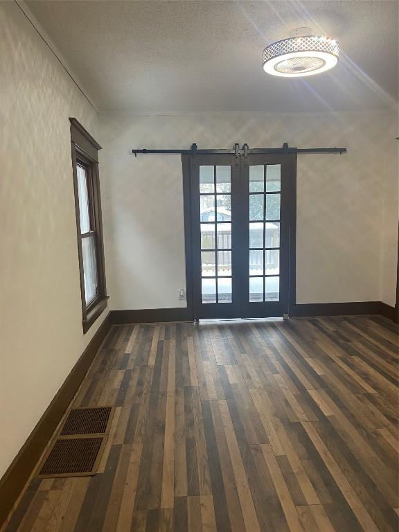 spare room featuring a textured ceiling, a barn door, and dark hardwood / wood-style floors