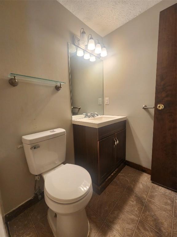 bathroom featuring a textured ceiling, toilet, and vanity