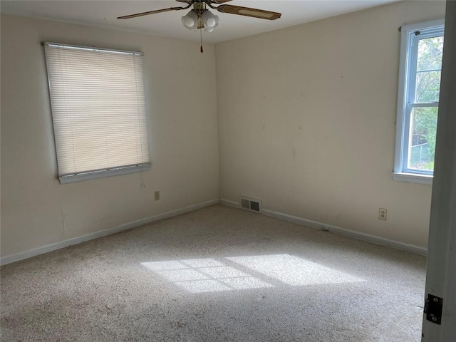 carpeted spare room featuring baseboards, a ceiling fan, and visible vents
