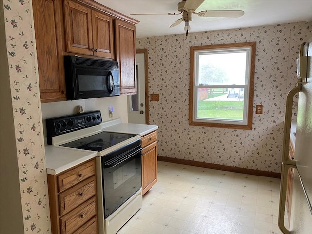 kitchen featuring electric range, black microwave, brown cabinets, light countertops, and wallpapered walls