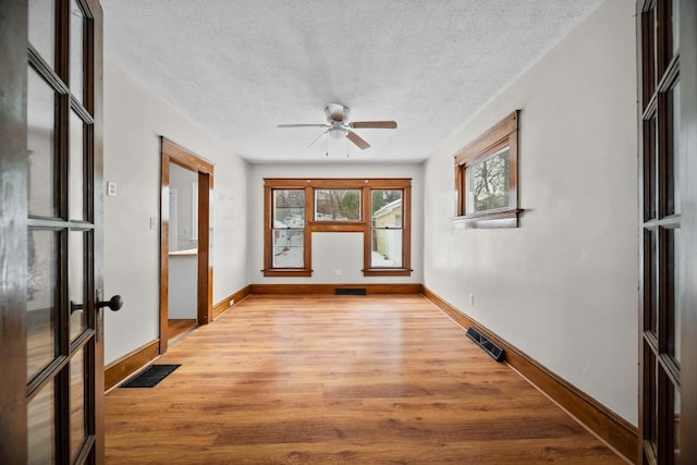 interior space featuring french doors, light hardwood / wood-style flooring, and a textured ceiling