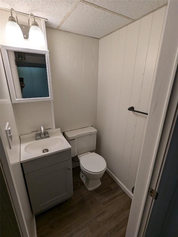 bathroom with hardwood / wood-style flooring, a paneled ceiling, vanity, and toilet