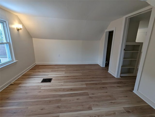 additional living space featuring vaulted ceiling and light wood-type flooring