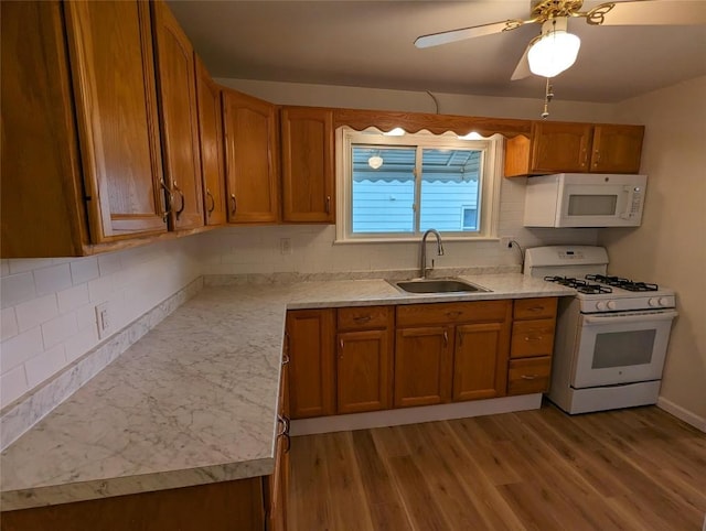 kitchen featuring sink, backsplash, white appliances, and light wood-type flooring