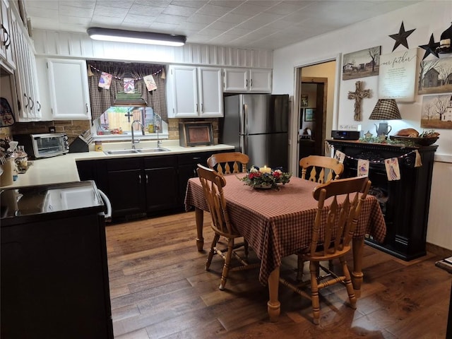 26418 State Highway 18, Albion, PA 16401 - kitchen featuring freestanding refrigerator, dark cabinetry, light countertops, light wood-style floors, and white cabinets