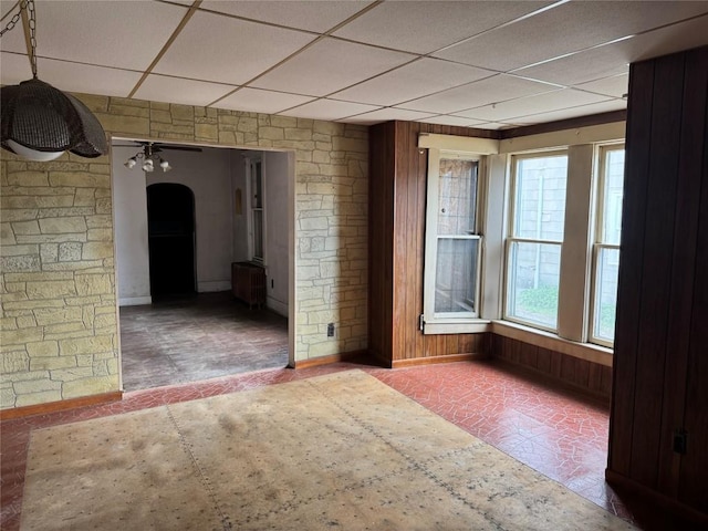 1029 E 25th St, Erie, PA 16503 - empty room featuring a paneled ceiling, radiator heating unit, arched walkways, wood walls, and a ceiling fan