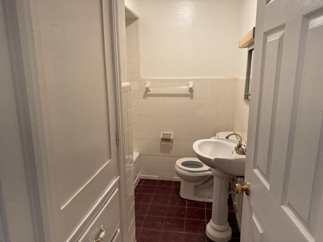 bathroom with tile patterned flooring, toilet, tile walls, and sink