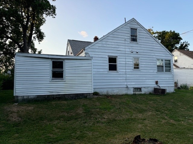 rear view of house featuring central AC unit and a yard