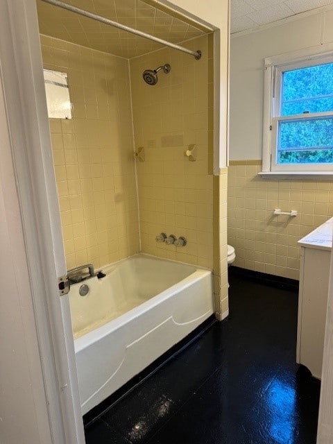 full bathroom with vanity, toilet, tile walls, and tiled shower / bath