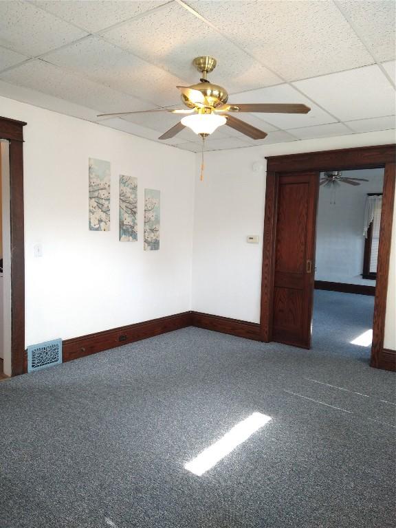 unfurnished room with carpet flooring, a paneled ceiling, and ceiling fan