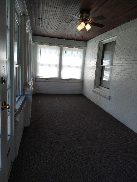 unfurnished sunroom featuring ceiling fan and wood ceiling