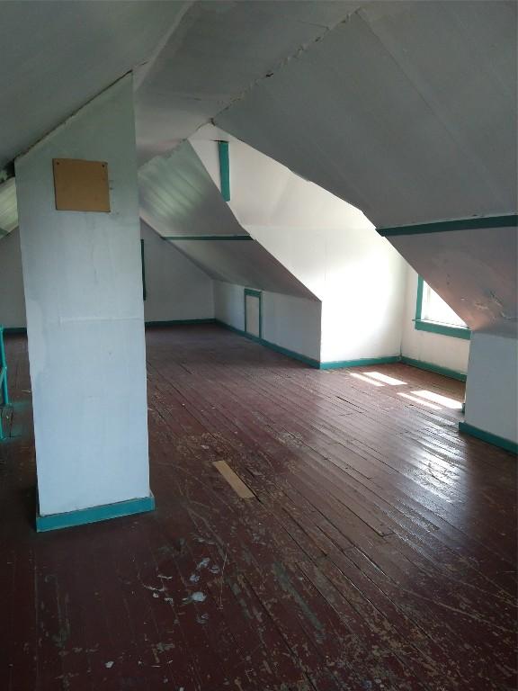 additional living space with dark wood-type flooring and vaulted ceiling