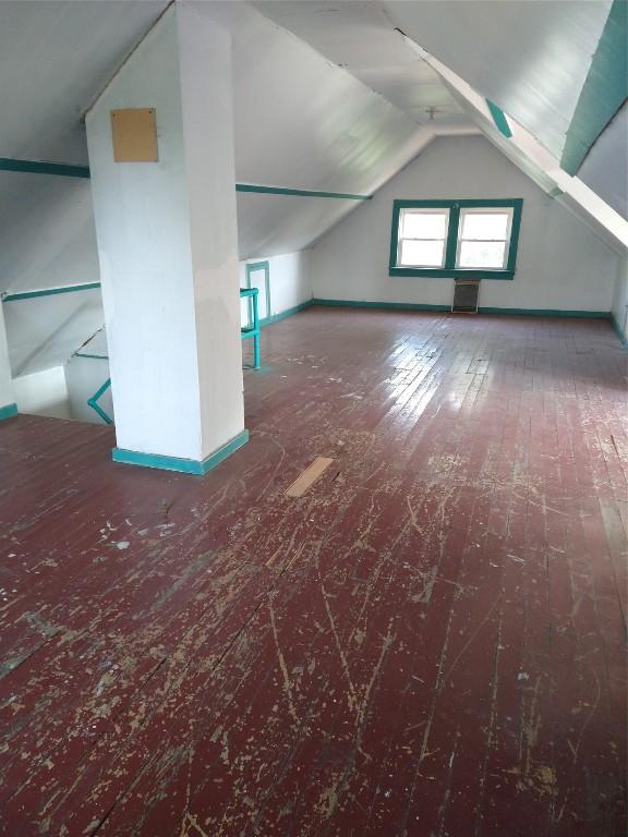 additional living space with dark carpet and lofted ceiling