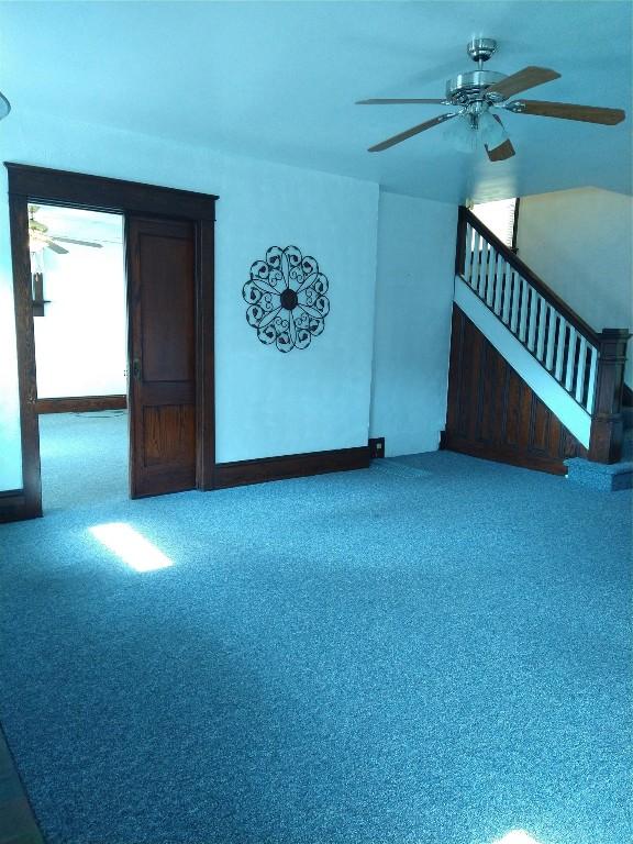 unfurnished living room featuring carpet floors and ceiling fan