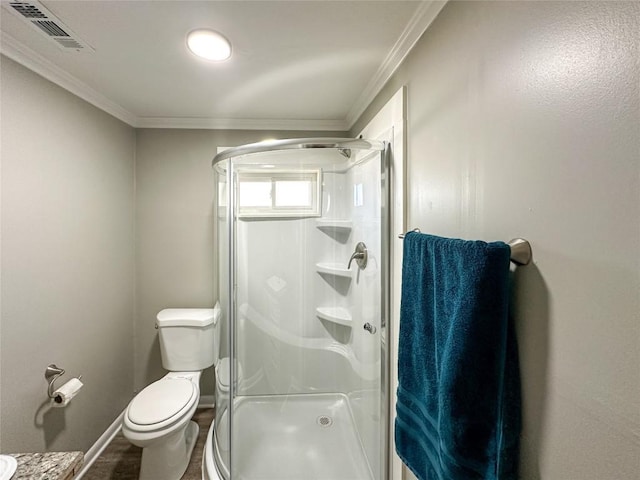 bathroom featuring toilet, ornamental molding, a shower stall, and visible vents