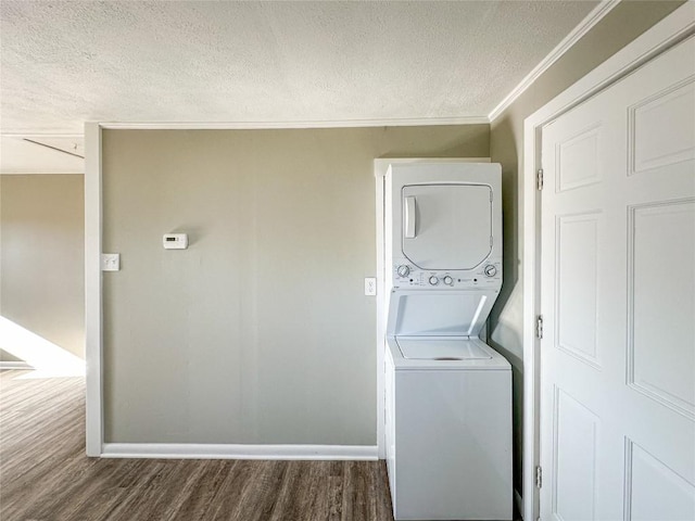 laundry room featuring a textured ceiling, laundry area, stacked washer / dryer, wood finished floors, and baseboards