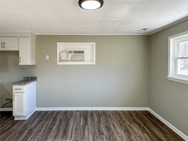 unfurnished dining area with dark wood-style floors, a textured ceiling, and baseboards