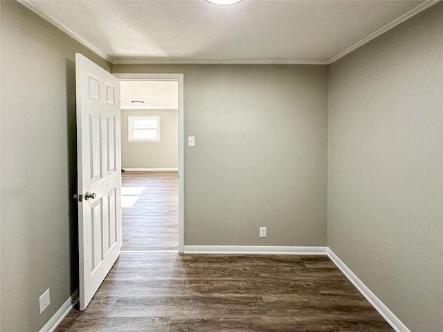 spare room with dark wood-style floors, crown molding, and baseboards