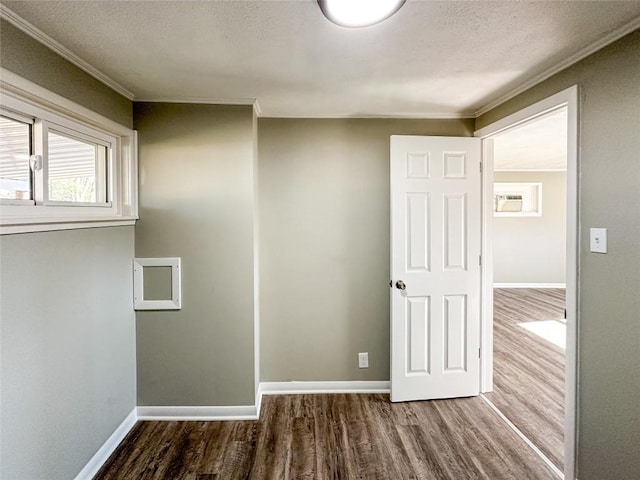 spare room with crown molding, a textured ceiling, baseboards, and wood finished floors