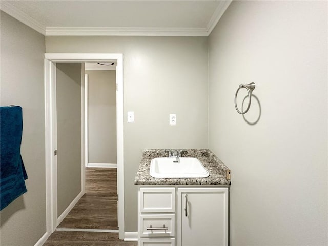 bathroom featuring crown molding, vanity, baseboards, and wood finished floors