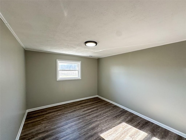 empty room featuring ornamental molding, a textured ceiling, baseboards, and wood finished floors